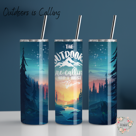 A stainless steel tumbler with a scenic outdoor design, featuring a mountain sunset, tall pine trees, and a reflection on a calm lake. The tumbler displays the phrase "Outdoors is Calling" in elegant script. The set includes tumblers with both metal straws and black flip-top lids. The background varies, including wood textures and white brick walls, enhancing the nature-inspired aesthetic.