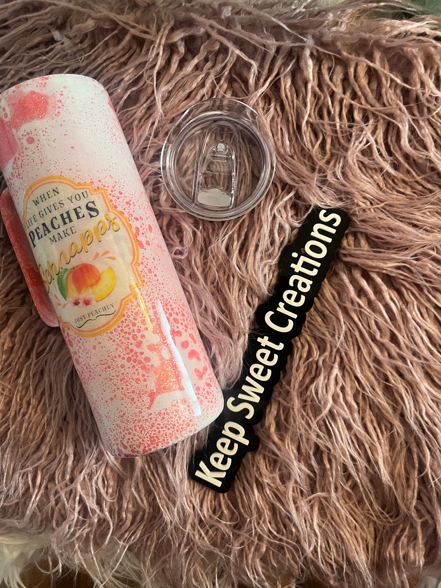 20 oz tumbler with handle, pink splatter design, mason jar graphic, and “When life gives you peaches, make peach schnapps” quote; includes lid and straw