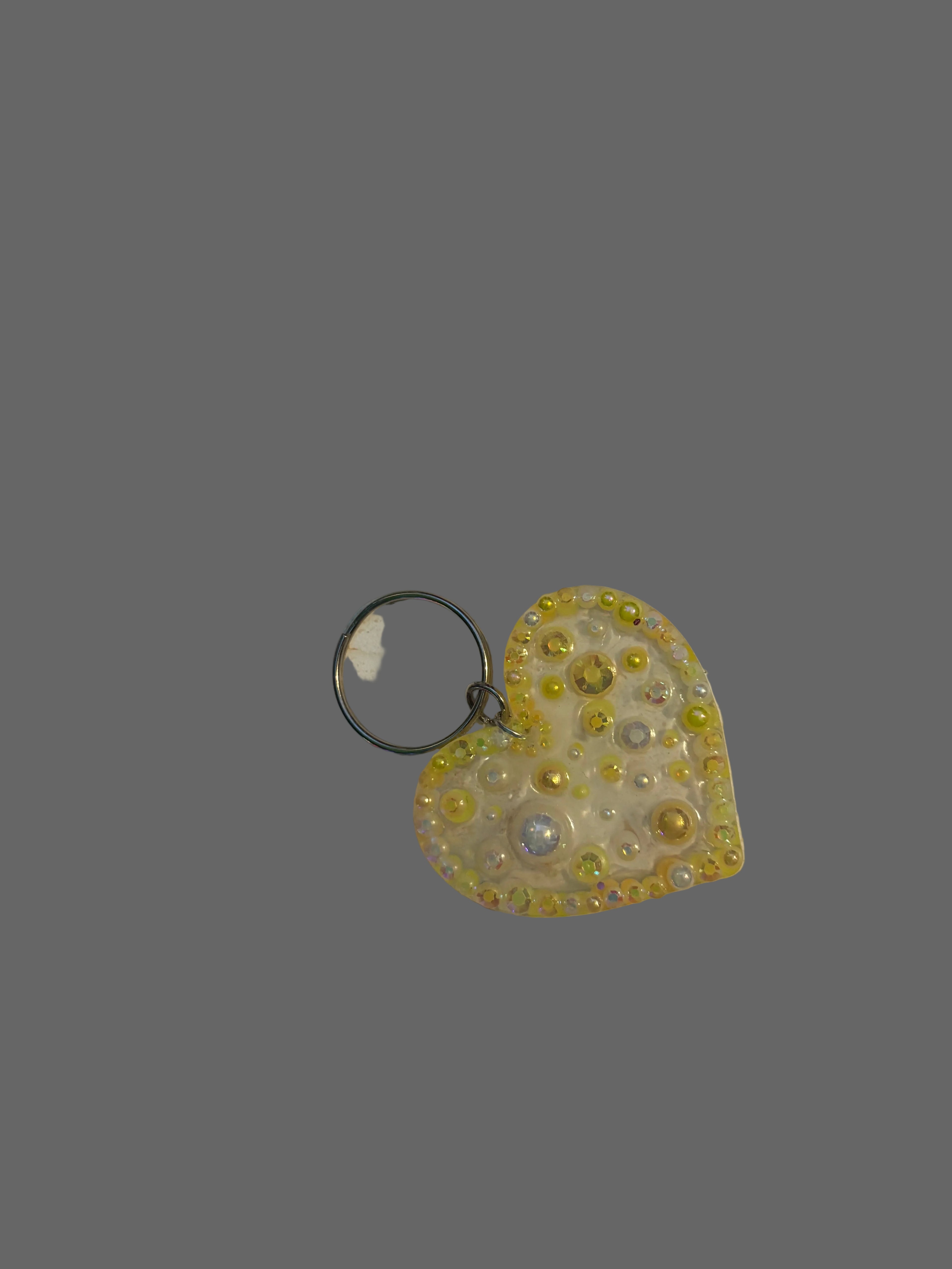 Heart-shaped keychain with yellow and silver design on a light-colored surface