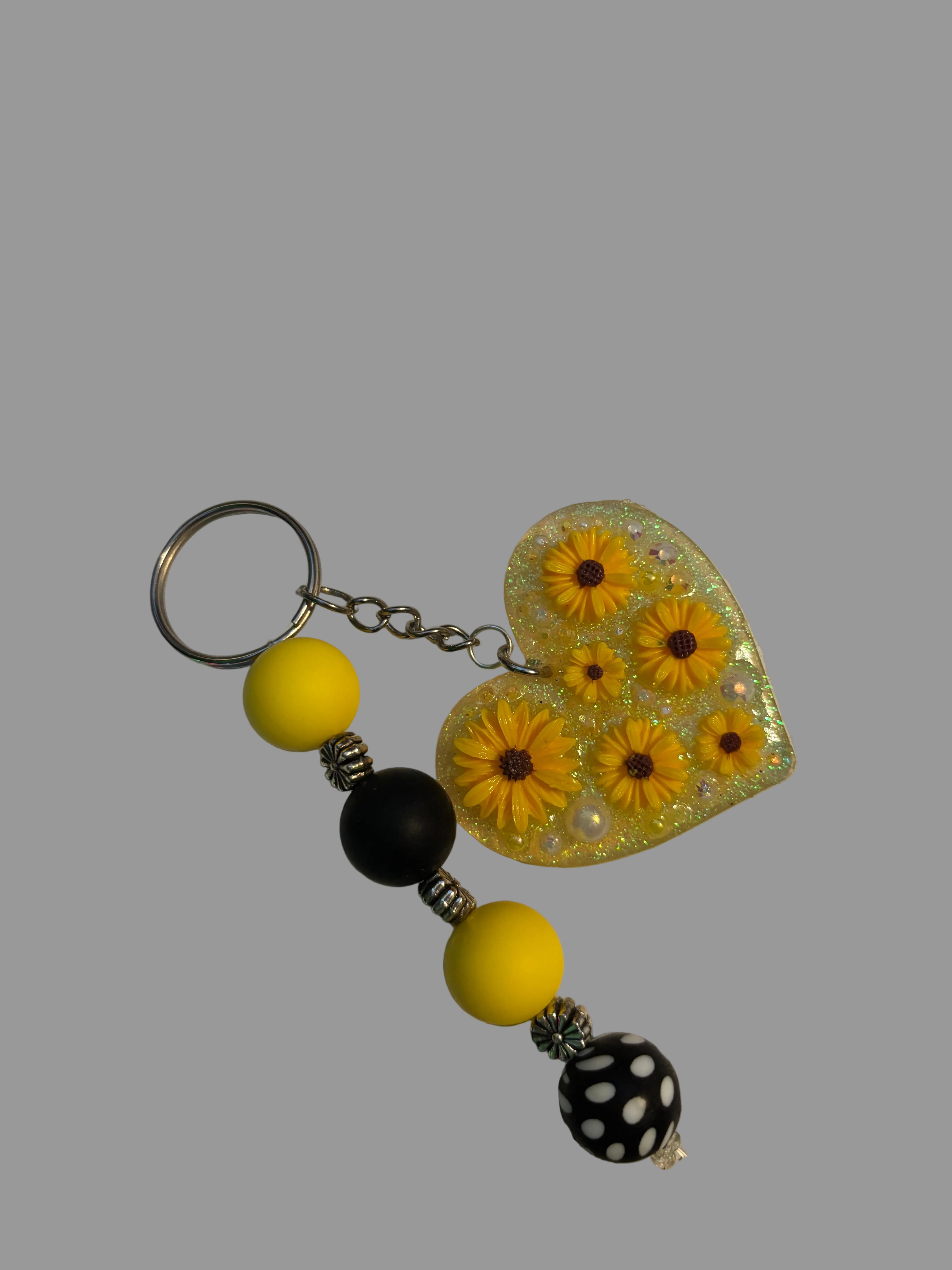 Keychain with heart-shaped floral design, yellow beads, and a black and white polka dot bead on a light background.