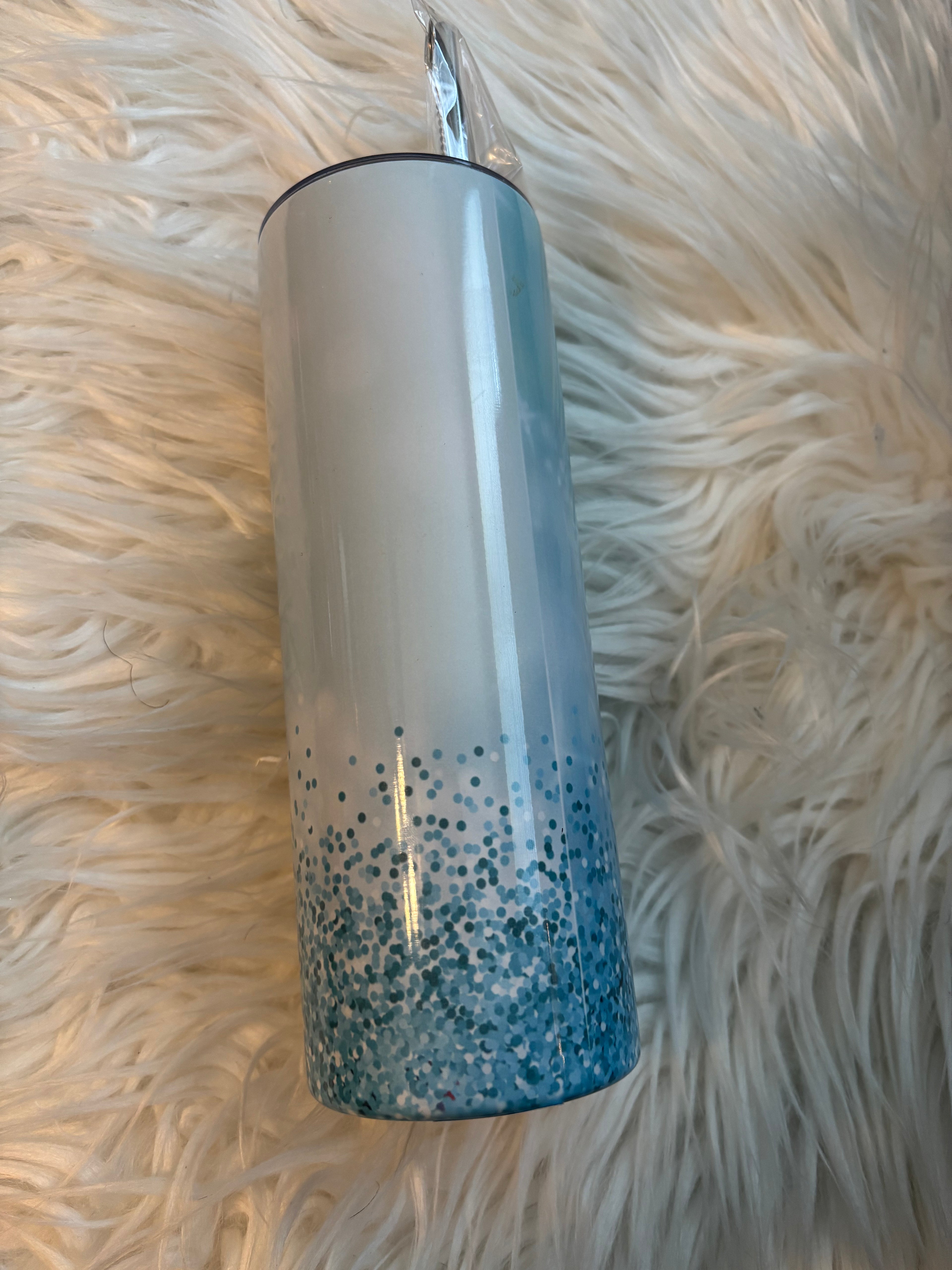 20 oz stainless steel tumbler with blue sparkles and a hummingbird design on a white faux fur background