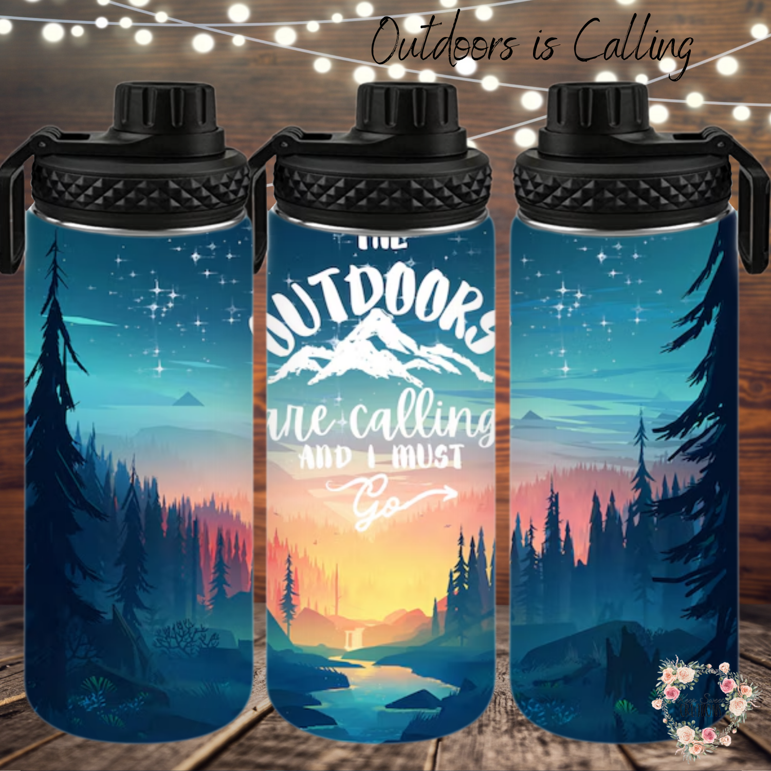 A stainless steel tumbler with a scenic outdoor design, featuring a mountain sunset, tall pine trees, and a reflection on a calm lake. The tumbler displays the phrase "Outdoors is Calling" in elegant script. The set includes tumblers with both metal straws and black flip-top lids. The background varies, including wood textures and white brick walls, enhancing the nature-inspired aesthetic.