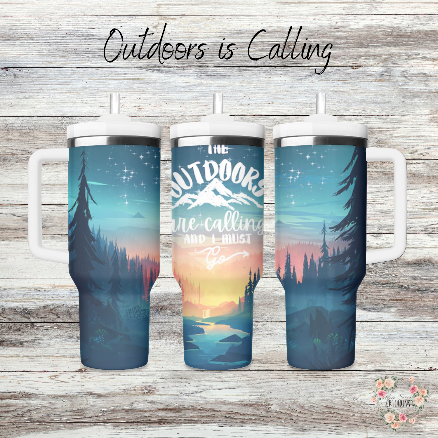 A stainless steel tumbler with a scenic outdoor design, featuring a mountain sunset, tall pine trees, and a reflection on a calm lake. The tumbler displays the phrase "Outdoors is Calling" in elegant script. The set includes tumblers with both metal straws and black flip-top lids. The background varies, including wood textures and white brick walls, enhancing the nature-inspired aesthetic.